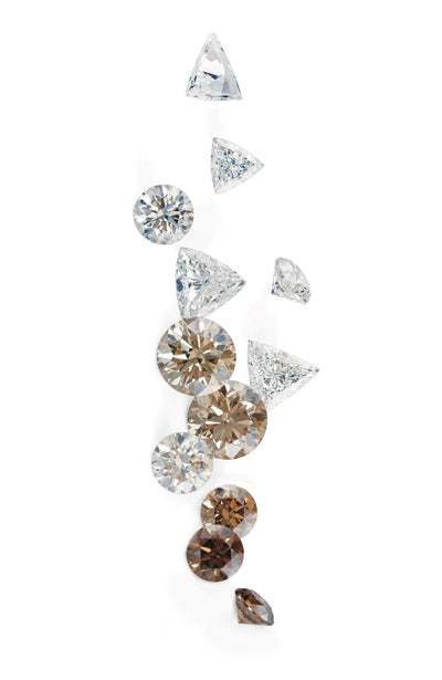 diamonds on a white surface in various shapes, following a colour gradient of dark brown to champagne and colourless brilliant diamonds