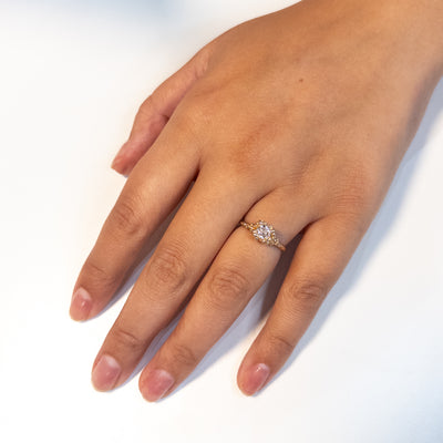 A gold ring featuring a central sparkling round old European cut diamond, surrounded by gold granules, worn on a hand.