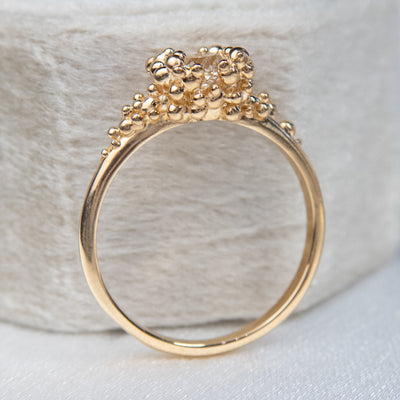 Side view of a gold ring featuring a central sparkling round old European cut diamond, surrounded by gold granules. 