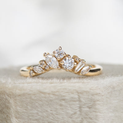 A delicate 14kt gold ring featuring a cluster of sparkling diamonds in various shapes, elegantly resting on a white velvet ring box.