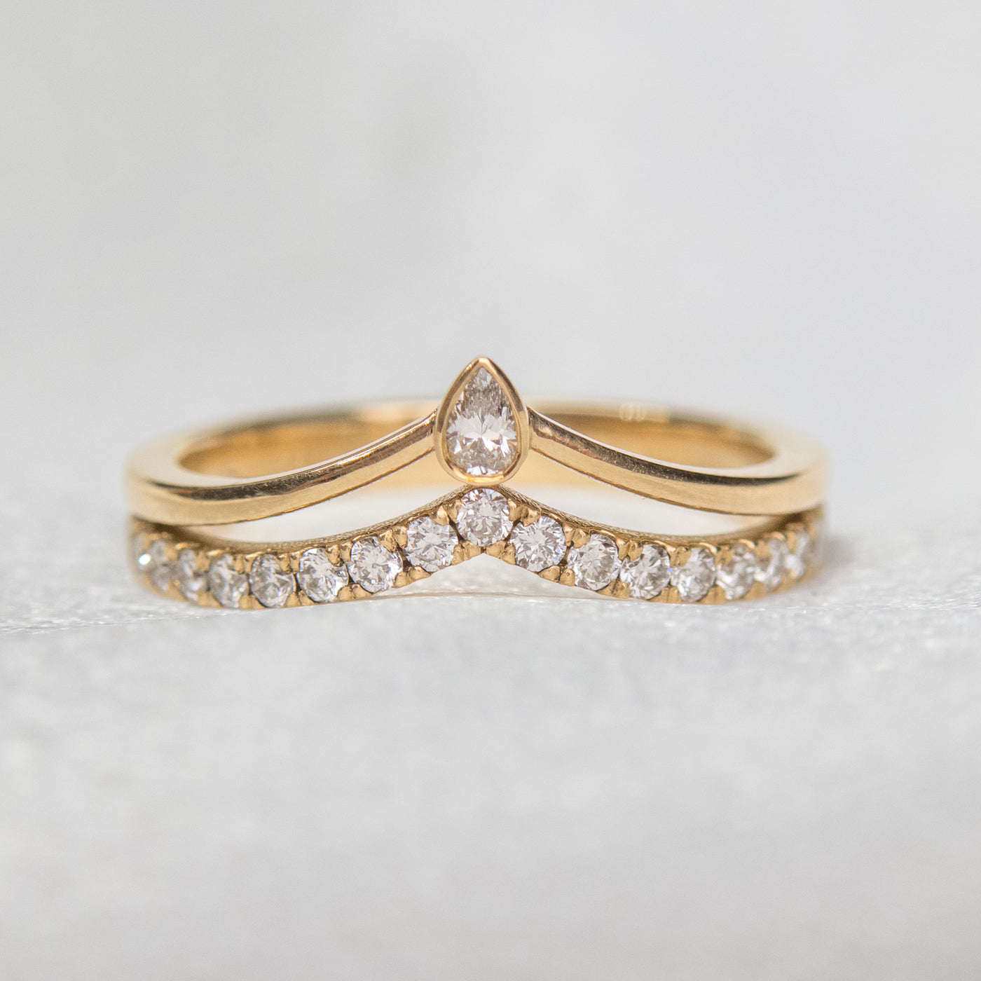 A delicate 14kt gold ring featuring a double peak design, adorned with sparkling pave diamonds and a pear diamond centerpiece.