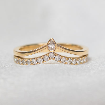 A delicate 14kt gold ring featuring a double peak design, adorned with sparkling pave diamonds and a pear diamond centerpiece.