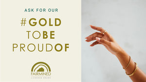 hand elegantly posed showing gold rings and bracelets, reaching towards the logo to show this is a Fairmined Licensed brand and that the gold used by this jeweller is ethical and responsibly sourced.