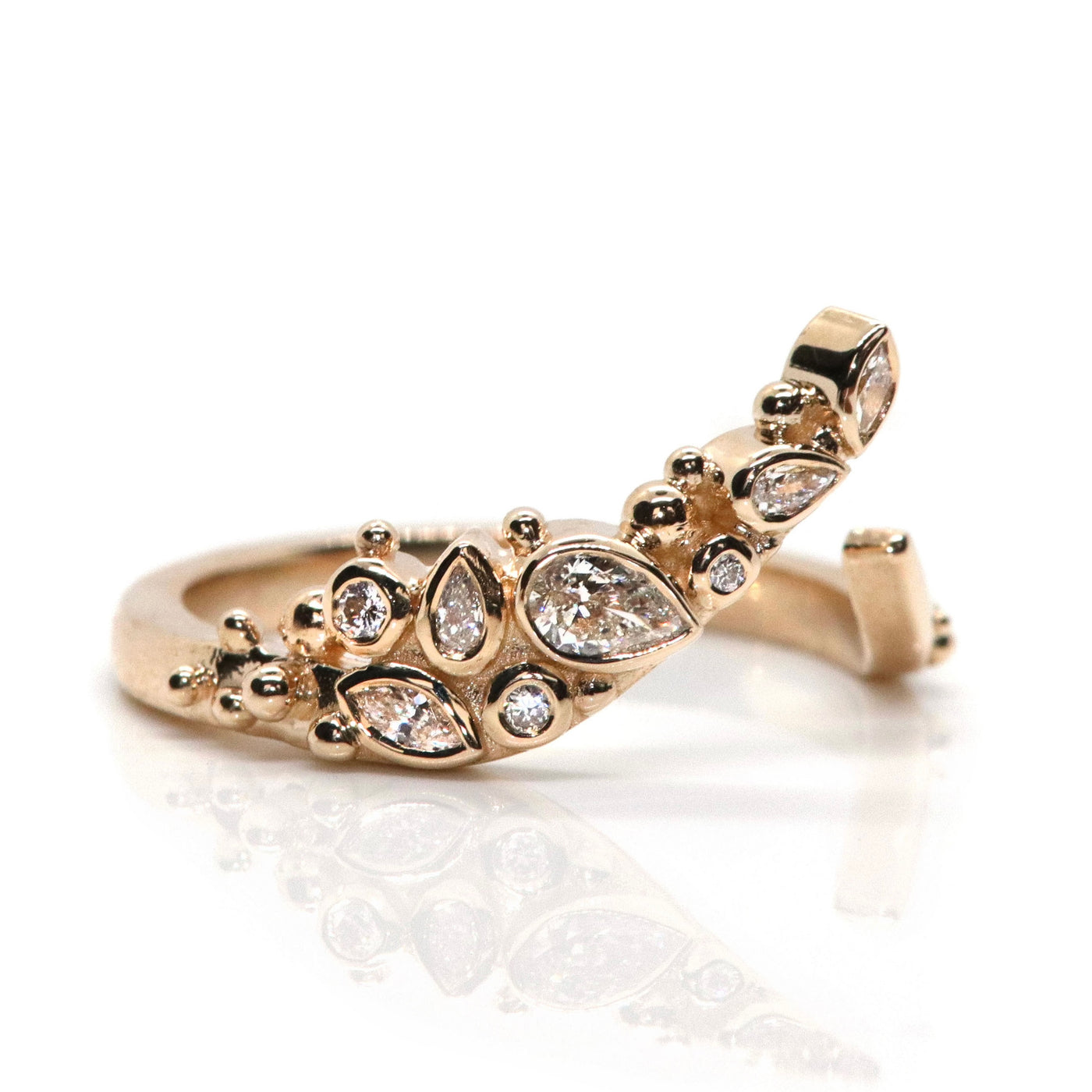 A delicate open gold ring featuring sparkling marquise, pear and round-cut diamonds set in an organic design, reflecting light beautifully shown from the side.