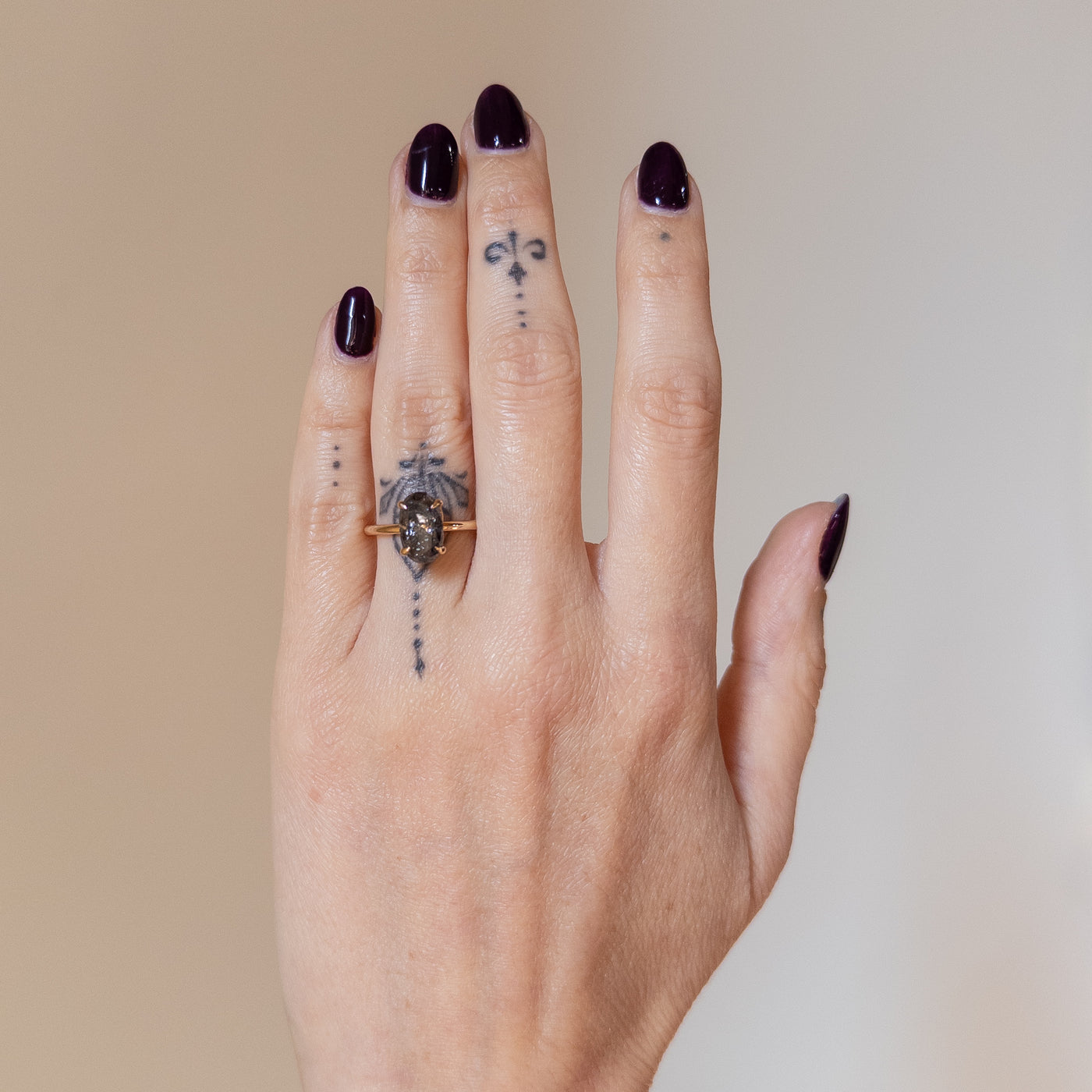 An elegant gold ring set with a large oval salt and pepper diamond. It features tiger-style prongs atop a decorative under basket. Worn on a hand. 