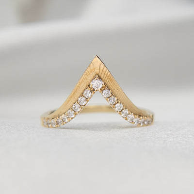 Elegant gold ring with a V-shaped design, encrusted with sparkling diamonds along the band.