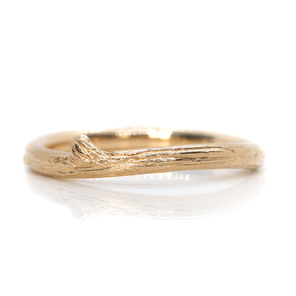 A delicate gold ring with a textured, nature-inspired design resembling a twisted twig.