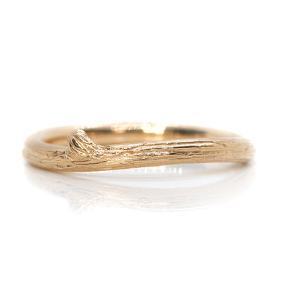 A delicate gold ring with a textured, nature-inspired design resembling a twisted twig.
