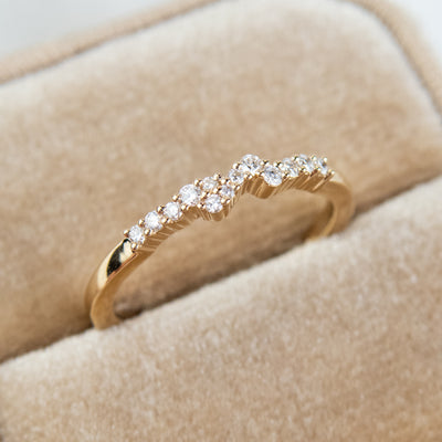An exquisite gold ring embellished with diamonds, reflecting a timeless elegance and opulence - tucked into a beige velvet jewelry box.