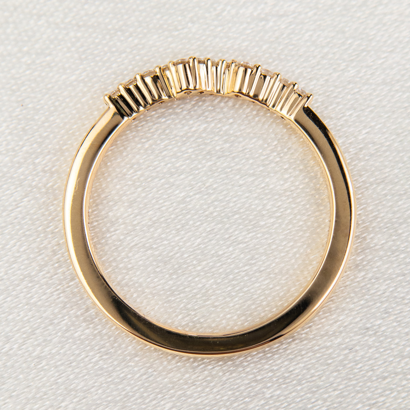 An exquisite gold ring embellished with diamonds, reflecting a timeless elegance and opulence - resting on white material.