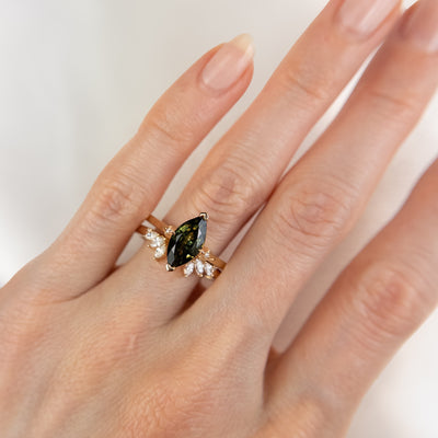 A unique 14KT yellow gold open ring with a combination of Round and Marquise Diamonds, shown on a hand stacked with a green marquise sapphire ring.