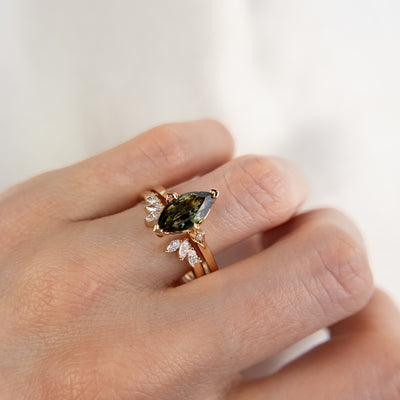 A unique 14KT yellow gold open ring with a combination of Round and Marquise Diamonds, shown on a hand stacked with a green marquise sapphire ring.