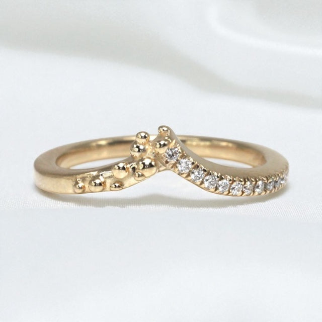 14K Yellow gold ring with diamond accents on one side and gold bubbles the other, contour to a soft peak to stack perfectly with an engagement ring. Shown on a white background.