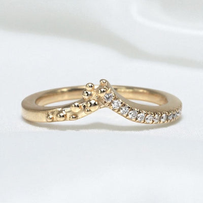 14K Yellow gold ring with diamond accents on one side and gold bubbles the other, contour to a soft peak to stack perfectly with an engagement ring. Shown on a white background.