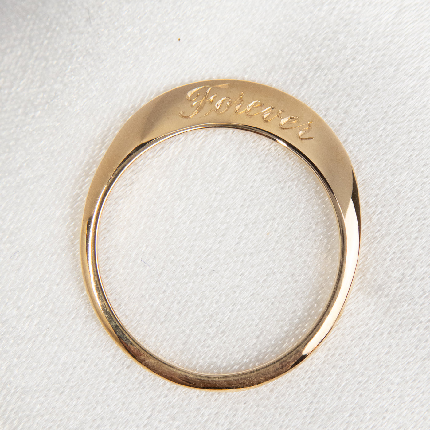 A stunning gold ring with a meaningful quote saying forever, shown from above.