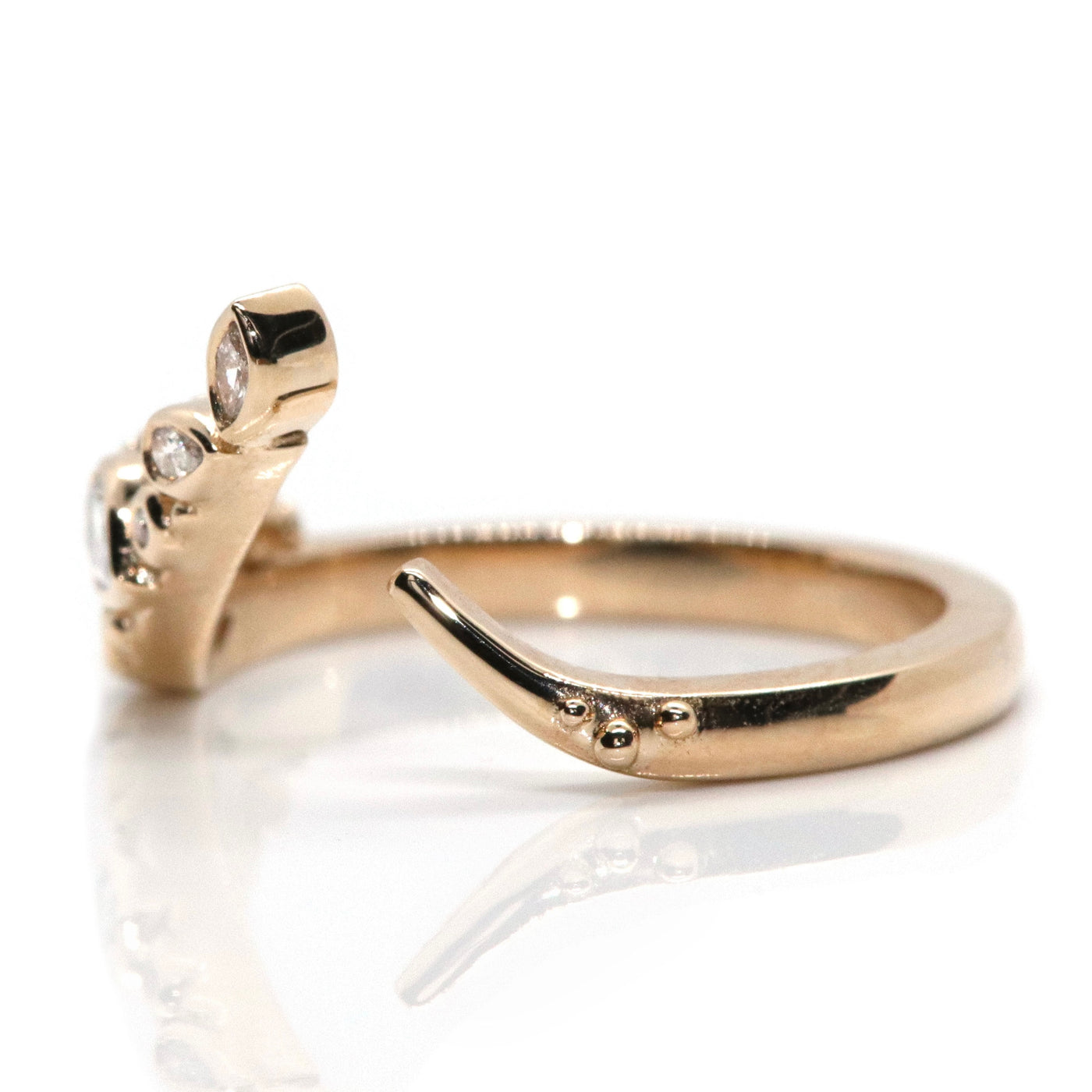 A delicate open gold ring featuring sparkling marquise, pear and round-cut diamonds set in an organic design, reflecting light beautifully shown from the side.