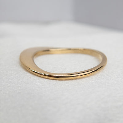 An exquisite gold ring showcasing a heartfelt quote, showing it's side profile laying on white fabric.