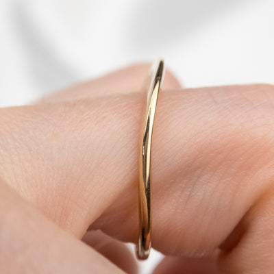 An exquisite gold ring showcasing a heartfelt quote, showing it's side profile on a finger.