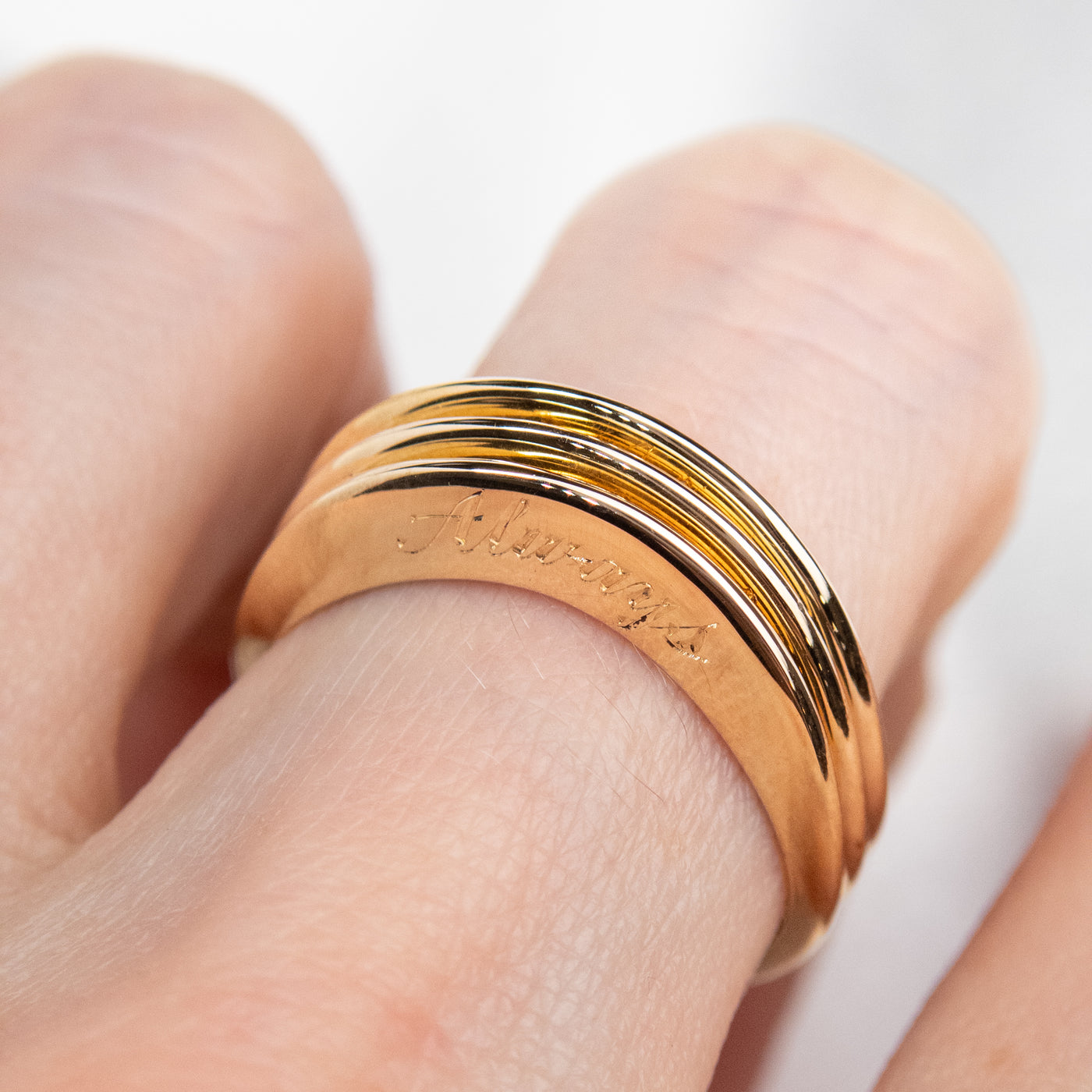 three stunning gold rings stacked together shown on a finger, showing an engraving of a special message.