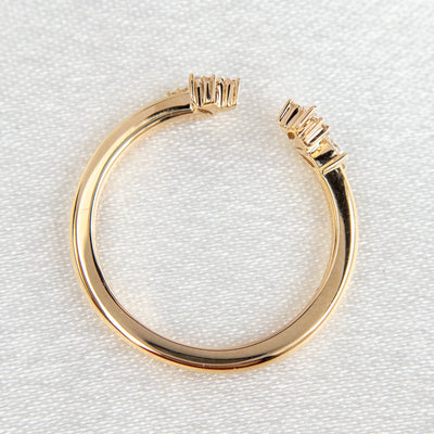 Gold open-ended ring with marquise and round cut diamonds on each end, set on a soft-focus light background.
