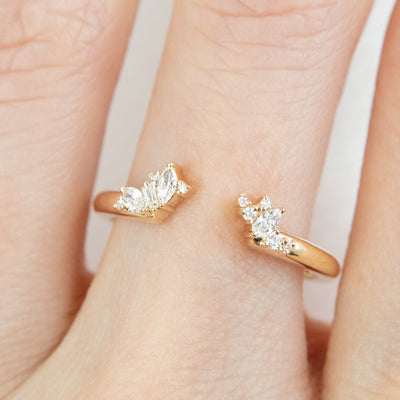 Gold open-ended ring with marquise and round cut diamonds on each end, pictured on a finger