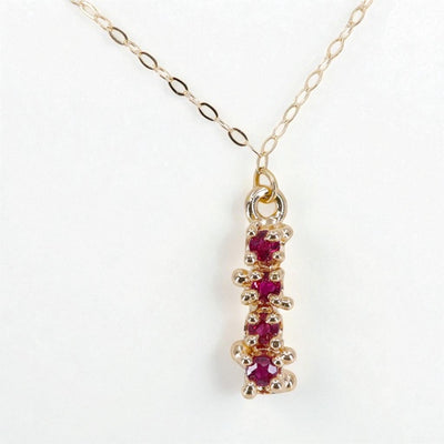 Gold necklace with 4 ruby gemstones on a white background