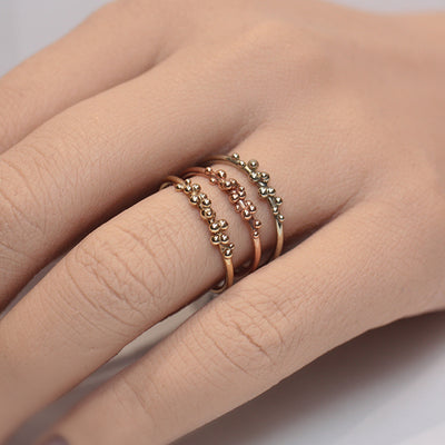 Rings in various metals including yellow gold, white gold and rose gold stacked on a finger featuring gold bubble details.