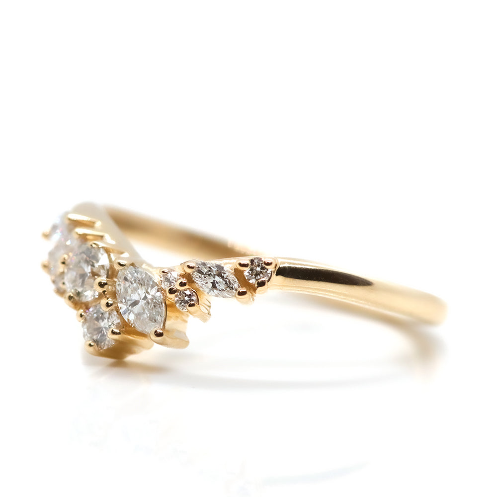 A delicate gold ring featuring an elegant arrangement of sparkling diamonds in various shapes, creating a stunning, unique design shown from the side
