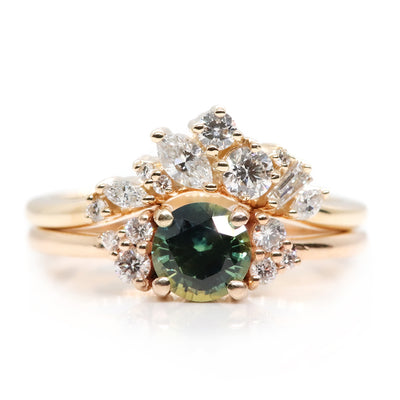 A delicate 14kt gold ring featuring a cluster of sparkling diamonds in various shapes, elegantly stacked with a round green sapphire engagement ring with diamond accents.