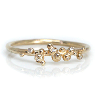 A delicate gold ring featuring a unique organic design with small bead-like accents and sparkling diamonds.