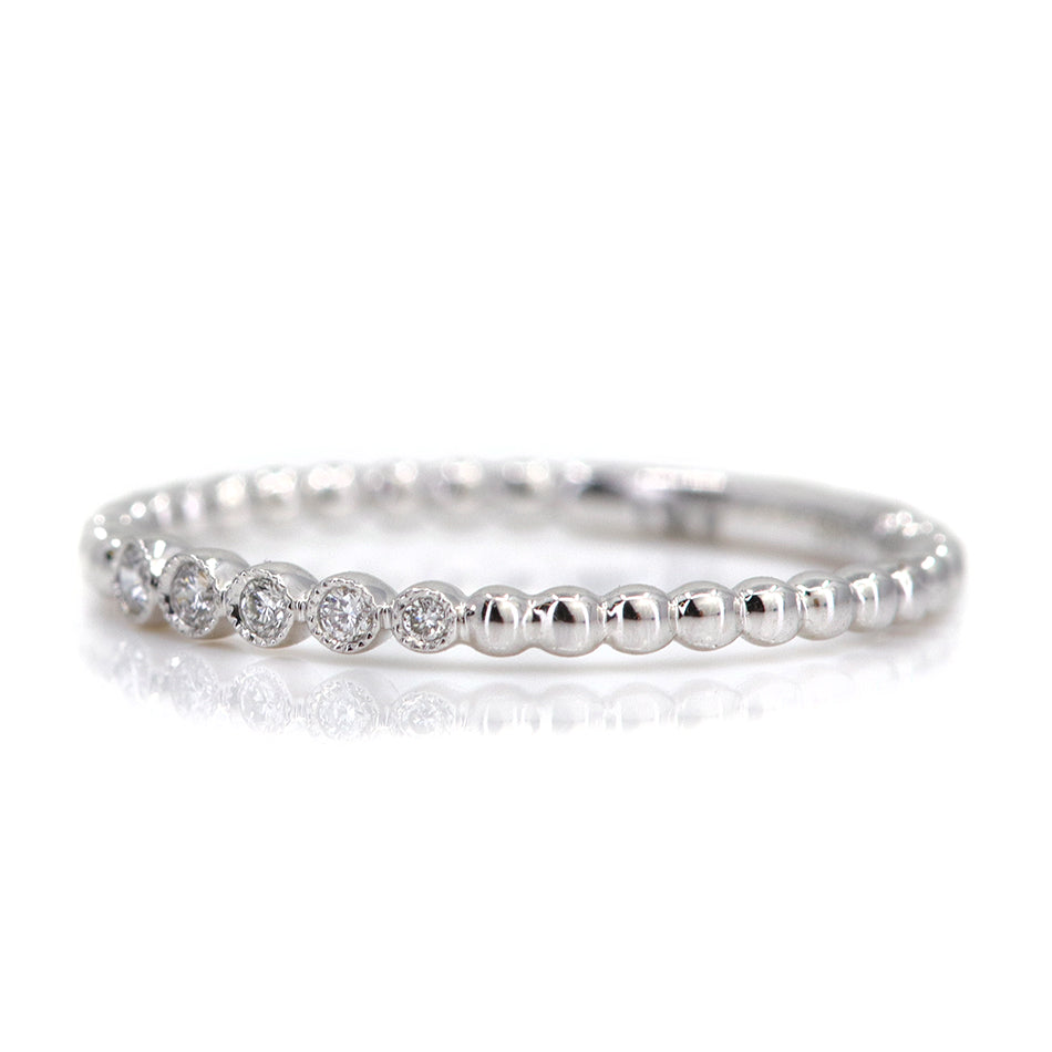 Elegant white gold ring featuring alternating shiny beads and five sparkling diamonds, set against a white background.
