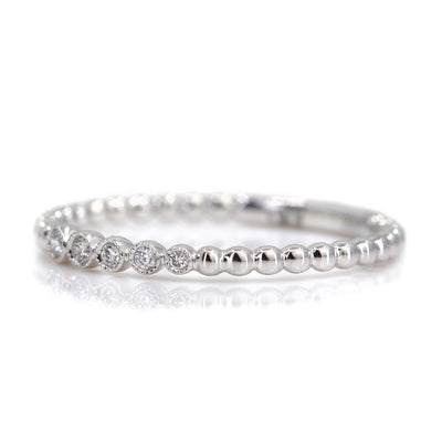 Elegant white gold ring featuring alternating shiny beads and five sparkling diamonds, set against a white background.