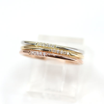 Simple and elegant stacking rings with rounded bands in different types of gold including white, rose and yellow gold, all with 5 pave diamonds, sparkle on a white surface.