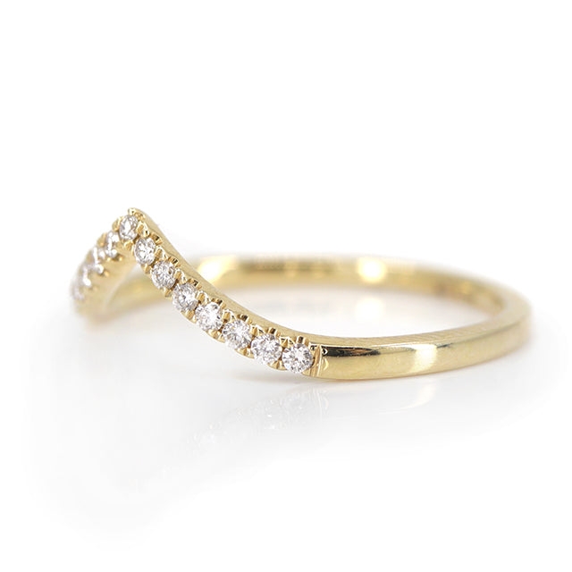 Elegant gold ring featuring a V-shaped or peak design adorned with sparkling diamonds along the band, reflecting light beautifully shown from the side.