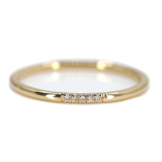 Simple and elegant gold stacking ring with rounded bands, with 5 pave diamonds, sparkle on a white surface.