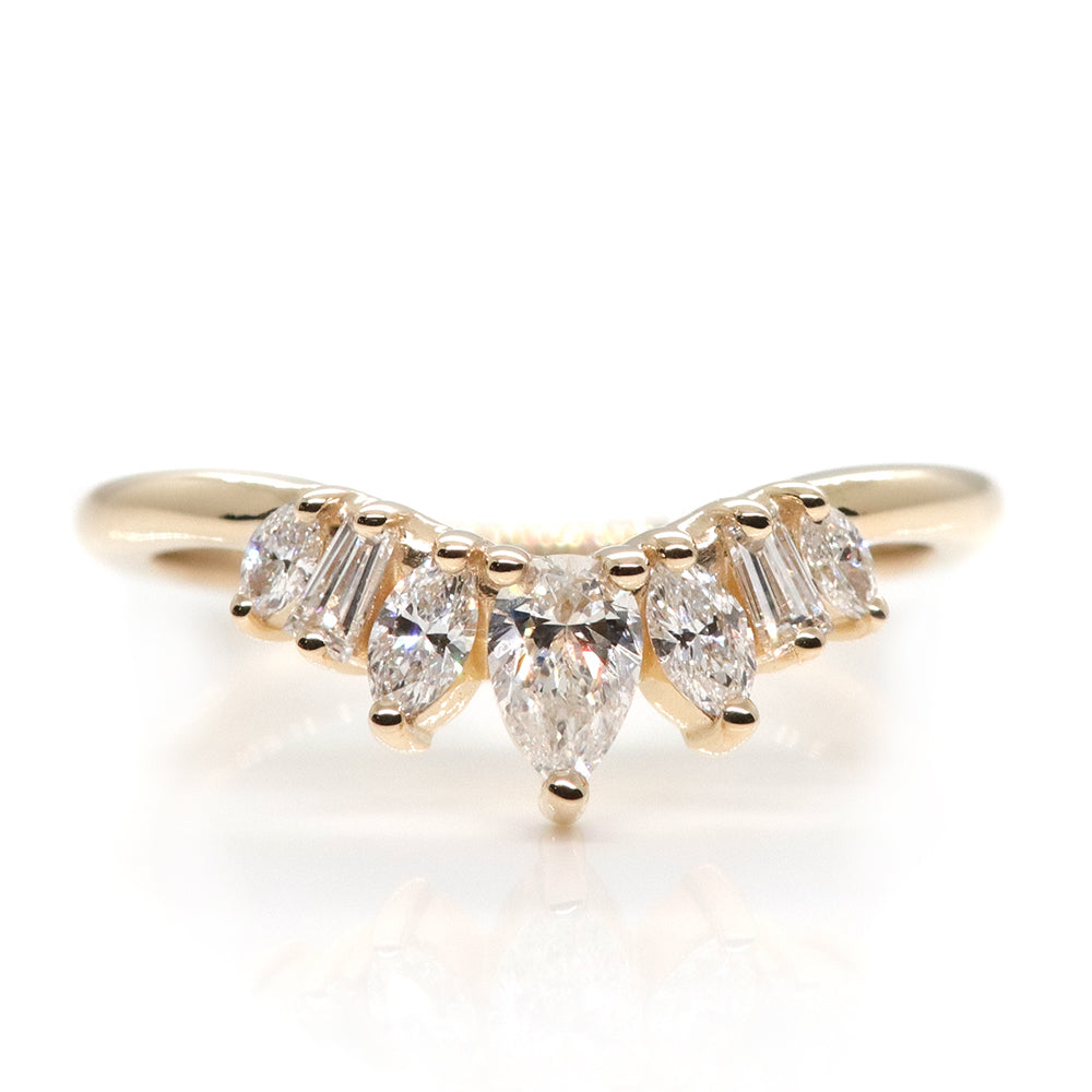 Peaked gold ring sparkles with 7 diamonds in oval, pear, marquise and rectangele shapes to form a crown appearance. Resting on a white background