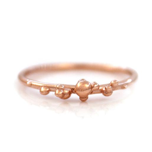 Rose gold stacking band with organic placed gold bubbles on a white background.