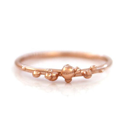 Rose gold stacking band with organic placed gold bubbles on a white background.