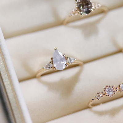 A three stone ring with a central fancy white pear-shaped diamond set in gold , flanked by two smaller pear diamonds. 
