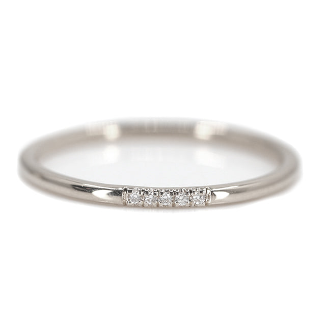 Simple and elegant white gold stacking ring with rounded band, with 5 pave diamonds, sparkle on a white surface.