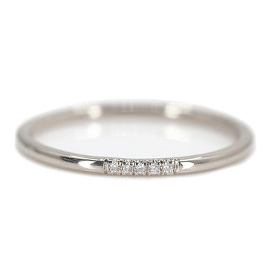 Simple and elegant white gold stacking ring with rounded band, with 5 pave diamonds, sparkle on a white surface.