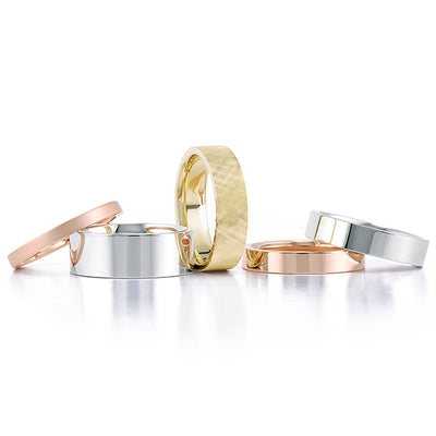 A collection of simple and elegant wedding bands in a variety of metals including yellow gold, rose gold and white gold. They vary in thickness and one has texture added to the band.