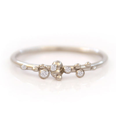 A delicate white gold ring featuring a unique organic design with small bead-like accents and sparkling diamonds.
