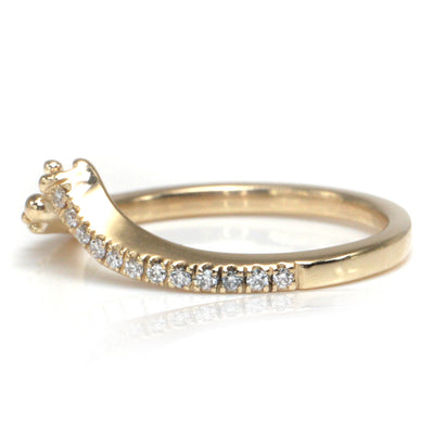 A delicate yellow gold ring featuring a curved design adorned with shimmering diamonds along one side and organically placed gold bubbles on the other shown from the side.