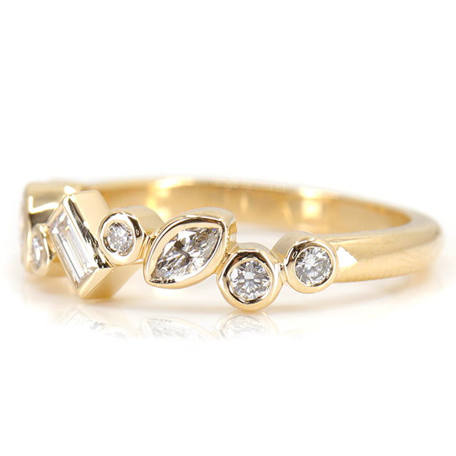 A stylish gold ring featuring assorted diamond shapes, including marquise, round emerald cut, set in a delicate bezel alternating design shown from the side.