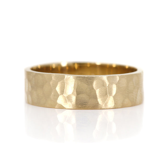 A satin finished gold ring with a hammered finish, showcasing a textured surface and a smooth interior, set against a white background.