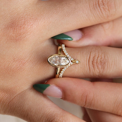 A diamond peaked wedding band stacked elegantly on a finger with a moval diamond engagement ring.