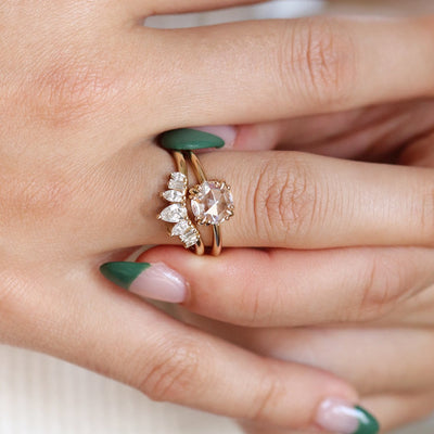 Peaked gold ring sparkles with 7 diamonds in oval, pear, marquise and rectangele shapes to form a crown appearance - stacked with a round rosecut diamond solitaire ring on a finger.